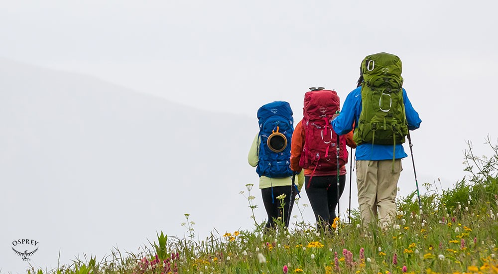 3 people backpacking on a hill