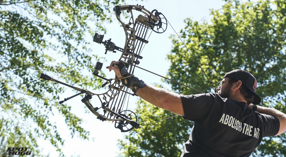 man holding a compound bow at full draw