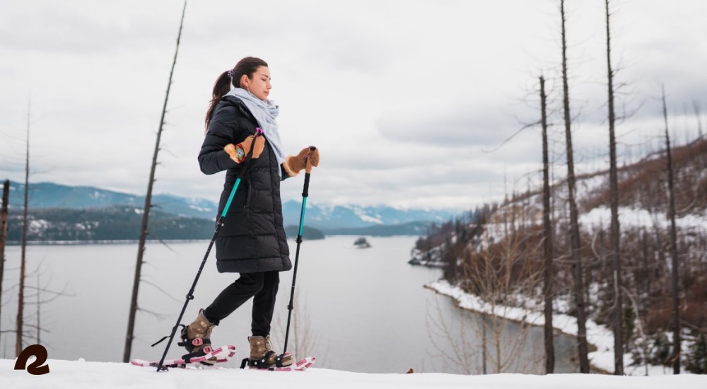 a woman out snowshoeing next to a lake