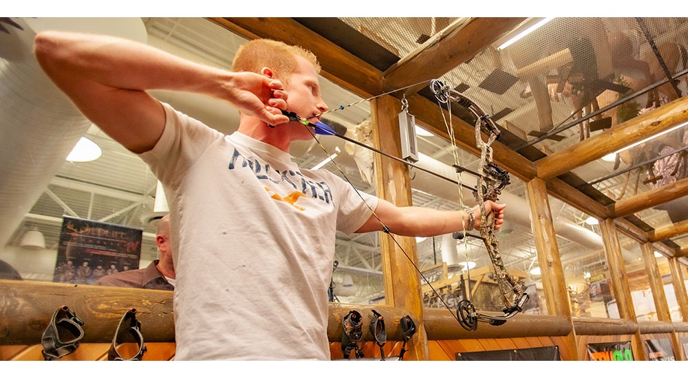 Guy shooting an archery bow at scheels