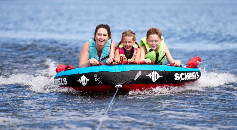 mom and kids wearing life jackets while tubing