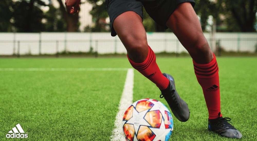 a player wearing adidas soccer cleats dribbling a ball