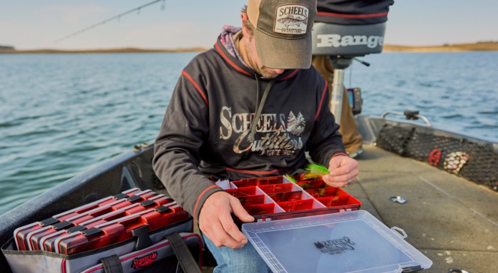 a fisherman with a scheels outfitters tackle box