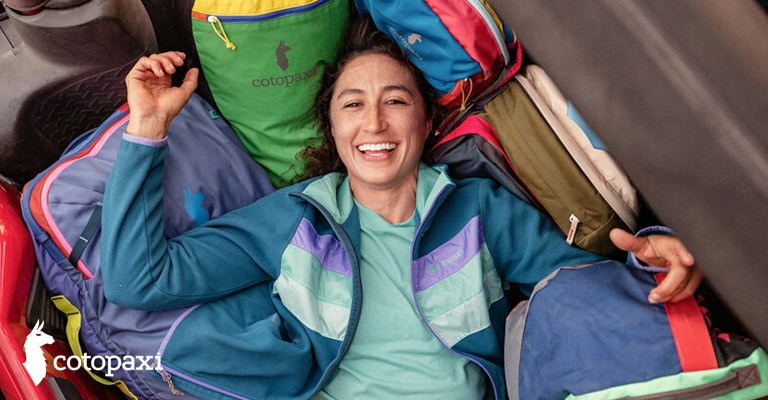 girl laying in a pile of backpacks