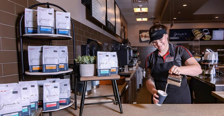 A Ginnas Cafe worker pouring a cup of coffee