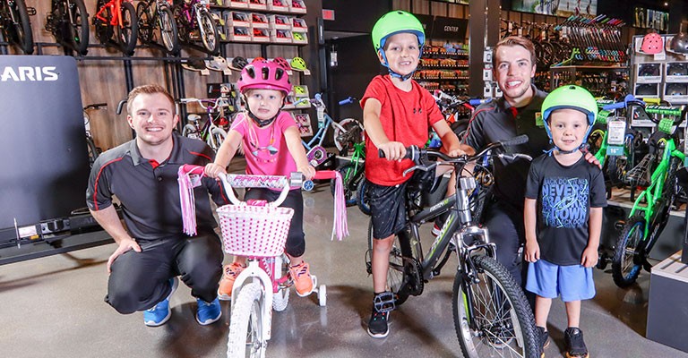 Scheels associate posing next to kids on their new bikes