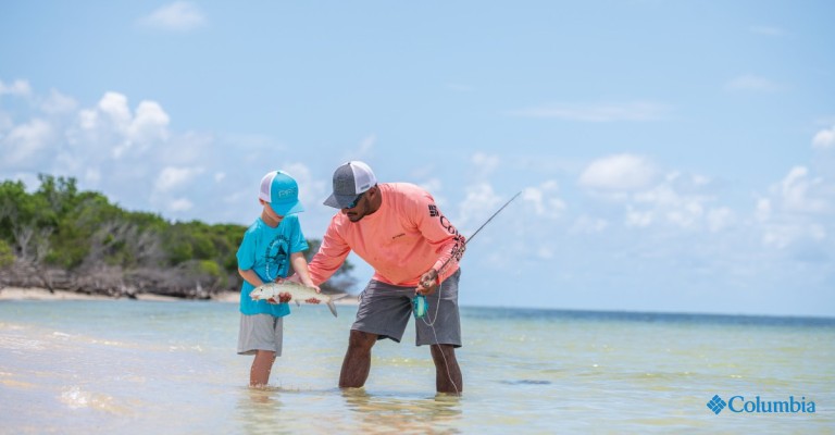 a father and son wearing sun protective clothing in the water