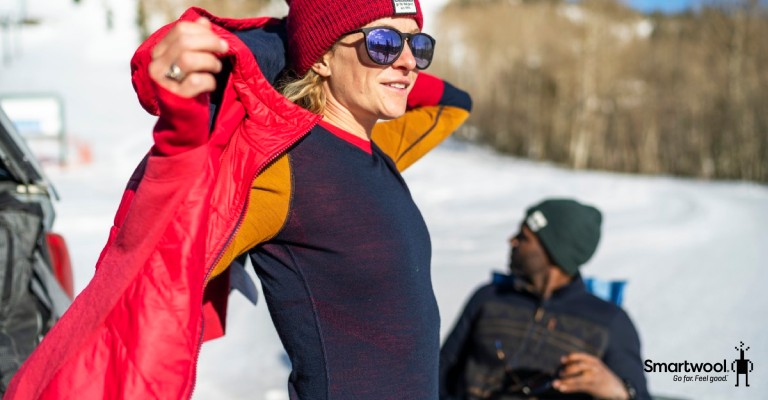 woman pulling on smartwool midlayer