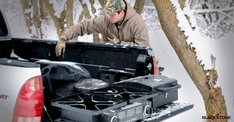 a hunter using his griddle on his truck bed