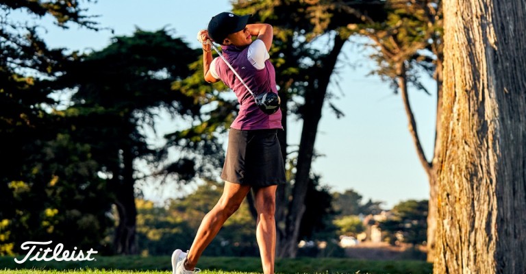 a woman teeing off with her golf driver