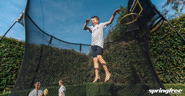 a boy jumping on a trampoline