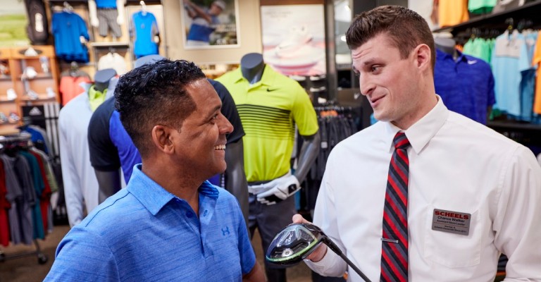 a scheels associate helping a customer with his golf trade in