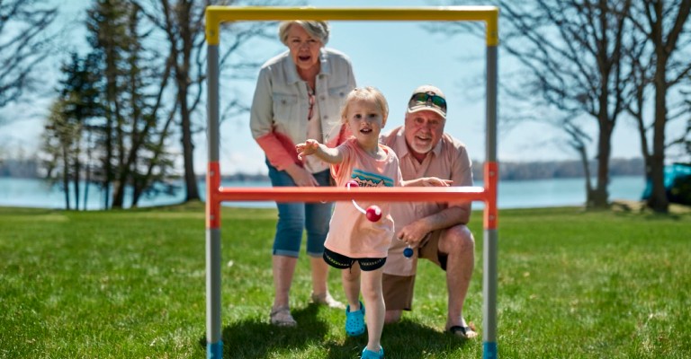 a girl playing yard games with her grandparents