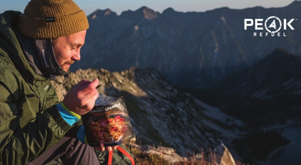 A man eating a Peak Refuel meal in the mountains.