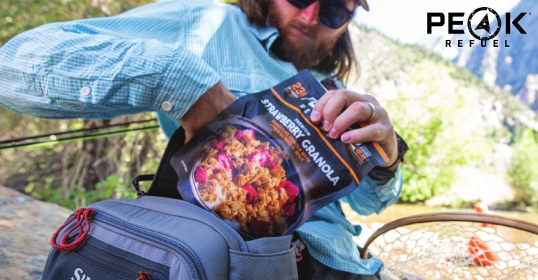 Man putting a Peak Refuel meal into his backpack.