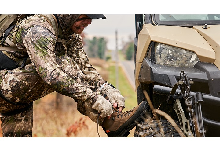 Hunter tying boots look on tire of UTV. 