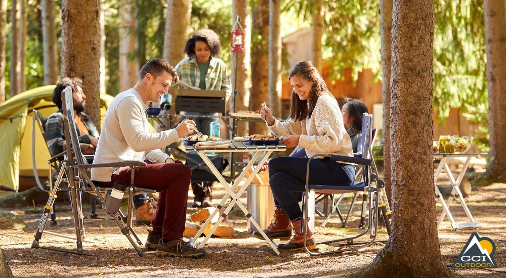 campers sitting in camping chairs enjoying a meal