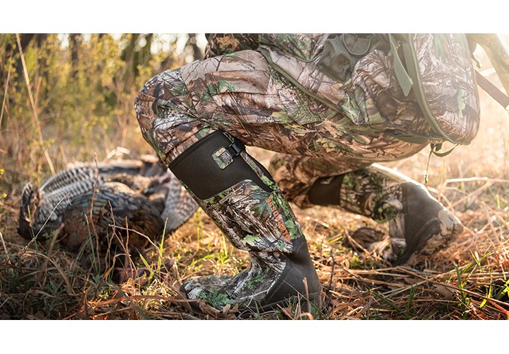 Turkey hunter bending over to admire harvest. 