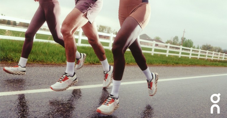 three people running Becoming on a road in the rain wearing on cloud white running Becoming shoes