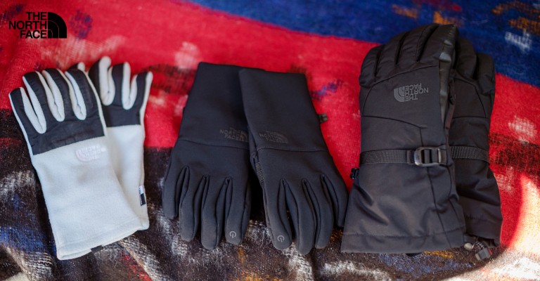 Three pairs of North Face gloves laid out on blanket