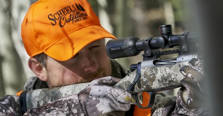 a hunter using a Swarovski rifle scope