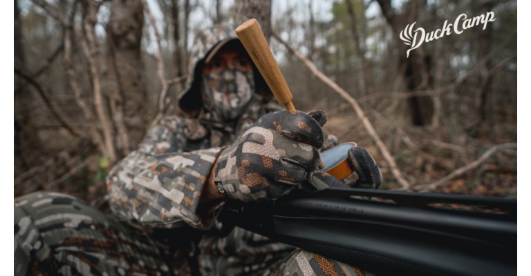 Hunter hunting turkeys wearing camouflage and using a pot style call