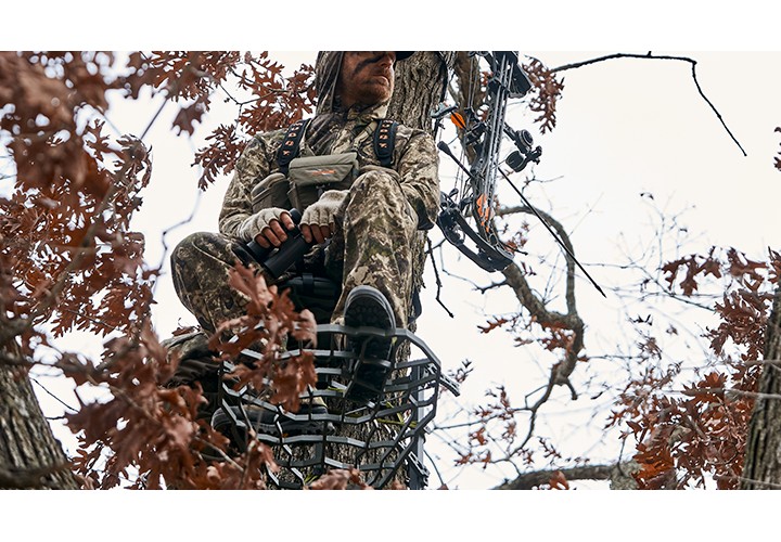 Archery hunter sitting in tree stand. 
