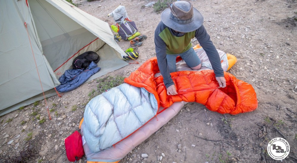 a camper zipping up his sleeping bag
