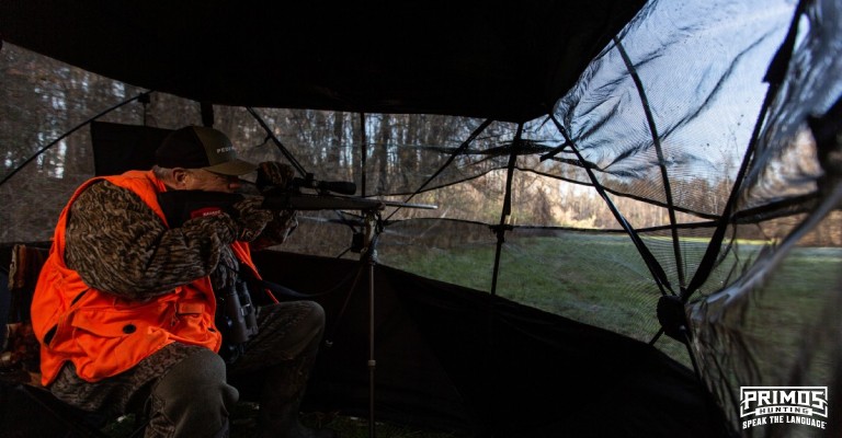 a hunter shooting a rifle from a ground blind
