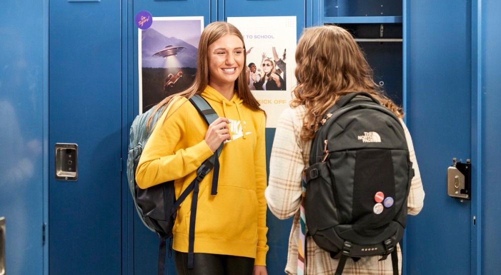 two girls visiting at their locker