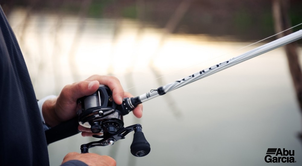 a fisherman holding a baitcasting rod and reel