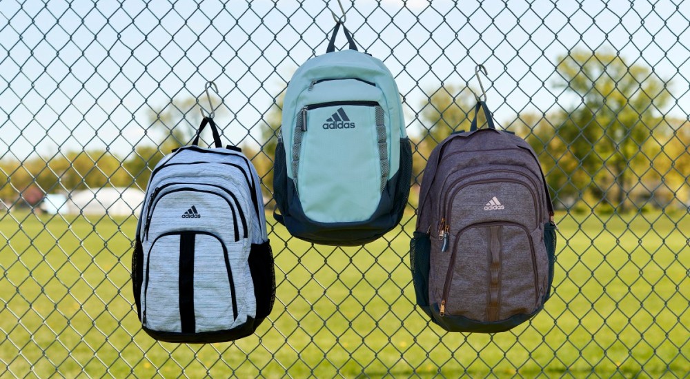 three backpacks hanging on a fence