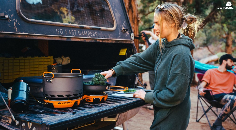 a girl using a jetboil camp stove to make dinner
