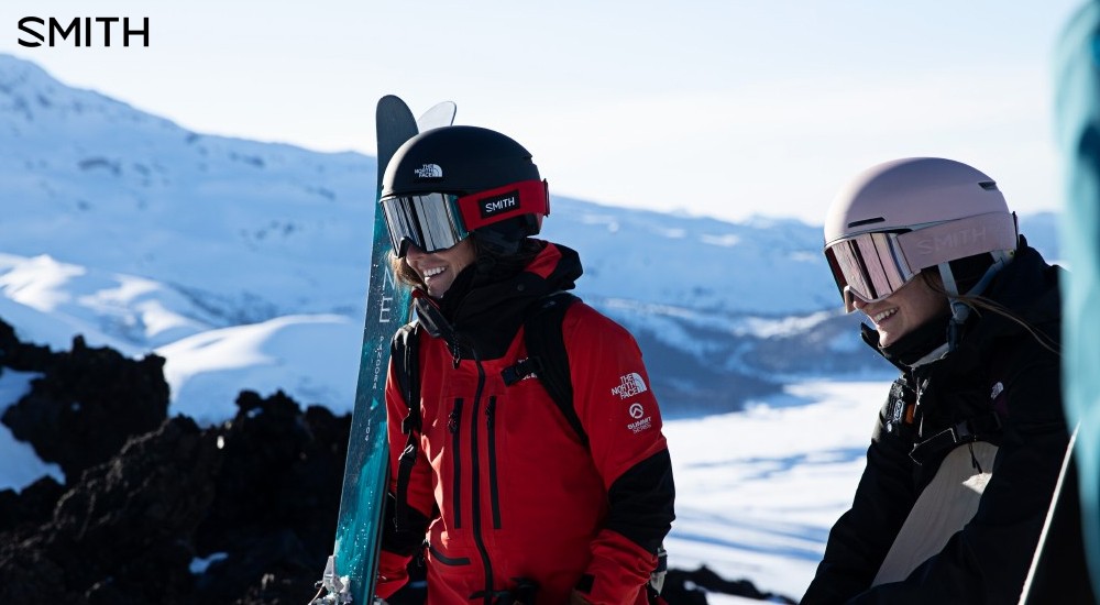 two female skiers wearing helmets and goggles on the slopes