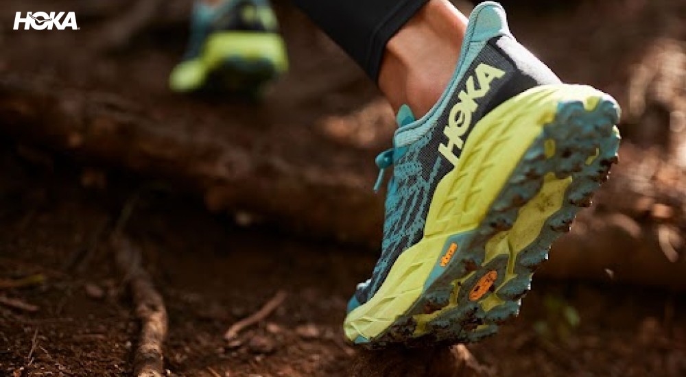 a runner wearing a hoka trail running shoe on trail terrain