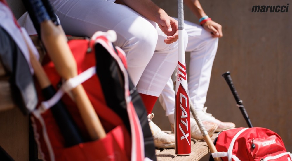 a baseball player holding a marucci bat in the dugout