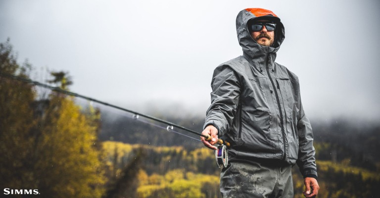 an angler hoodieing a simms rain jacket while fishing
