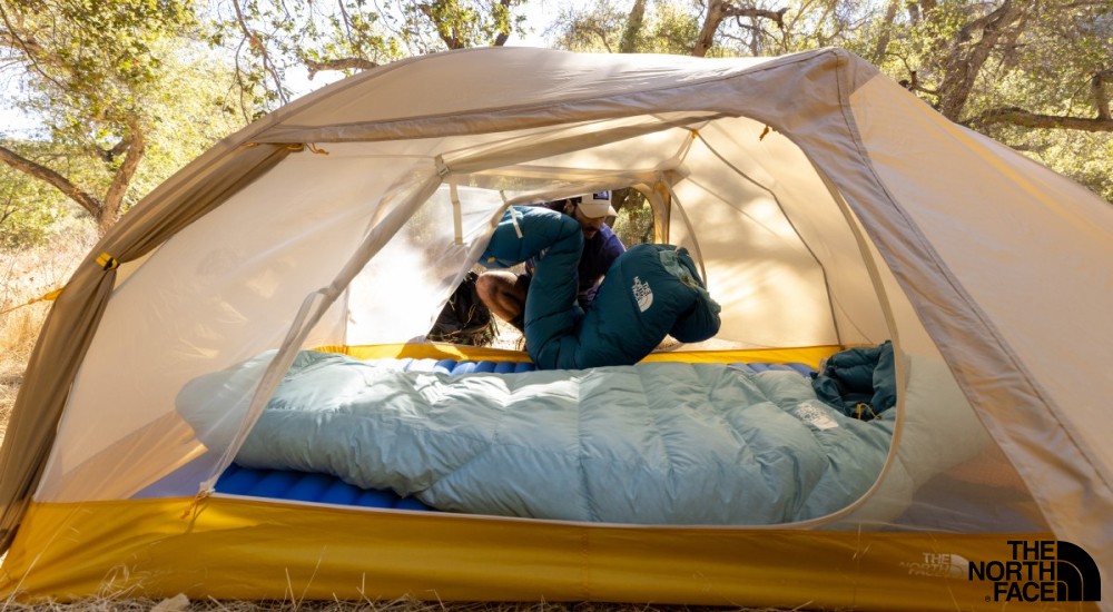 a man putting the sleeping bags in a tent