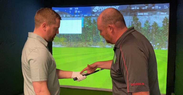 a golf fitting expert helping a customer in the golf simulator