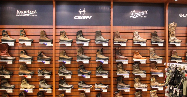 a variety of hunting boots on a wall within the hunting shop
