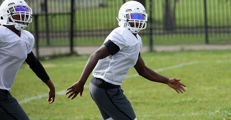 Close up two football players running in lower body protective equipment