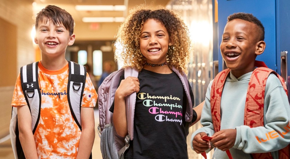 three kids wearing backpacks on the first day of school