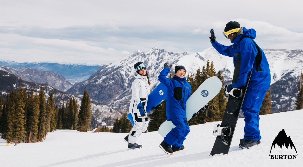 two kids and an adult getting ready to snowboard