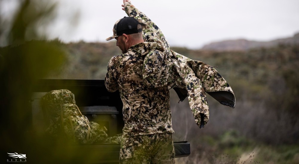 a man putting on his hunting jacket over his other layers