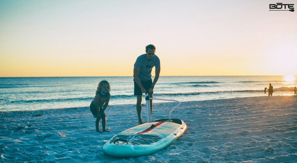 a dad inflating his paddle board with his kid