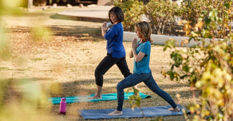 two women doing yoga outdoors on their yoga mats