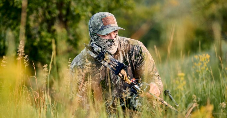 a hunter hiding in the field while wearing V2 camo