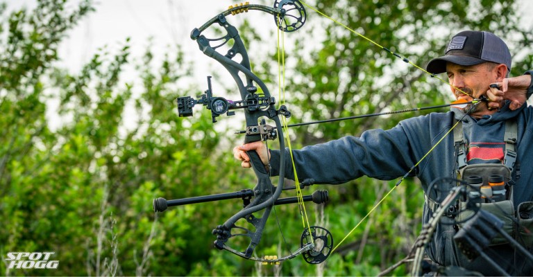 a hunter using a bow sight to aim his compound bow