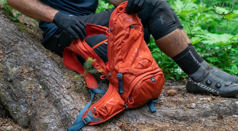 a man opening his backpack while on a hike