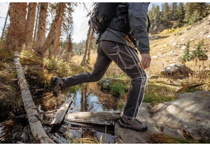 Man outside walking across small stream 